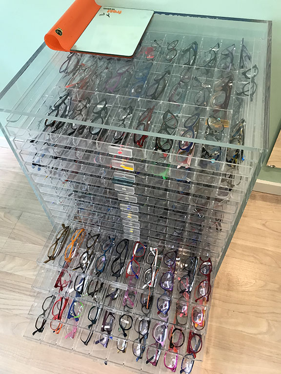 Et stort udvalg af briller vist i et møbel hos optiker.