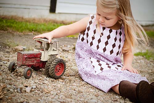 Flicka som leker med en traktor. Visuell utveckling hos barn.