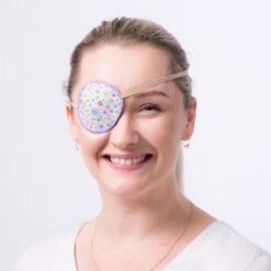 En ögonlapp med resår för vuxna. Den är vit med lila kant och små lila och ljusrosa blommor. Märket är Kay Fun Patch. Den heter Cornflowers. Model.